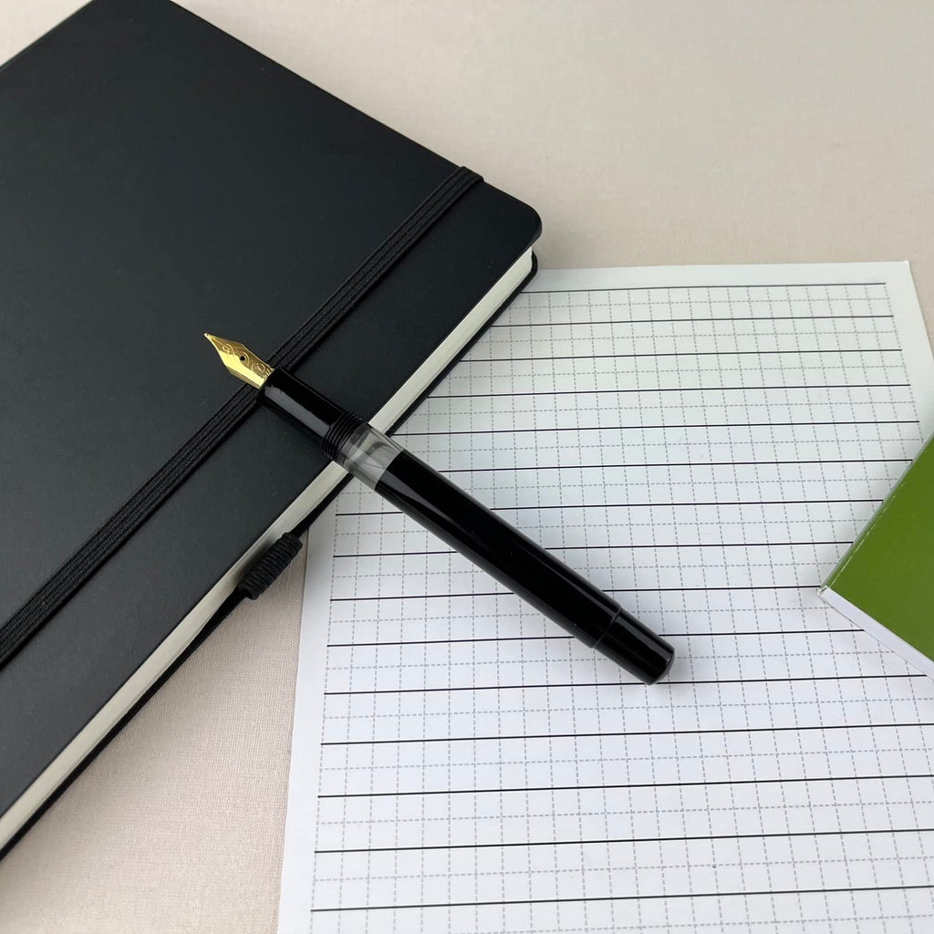 Scrikss 419 Medium Nib Fountain Pen in Black GT on a squared sheet and diary
