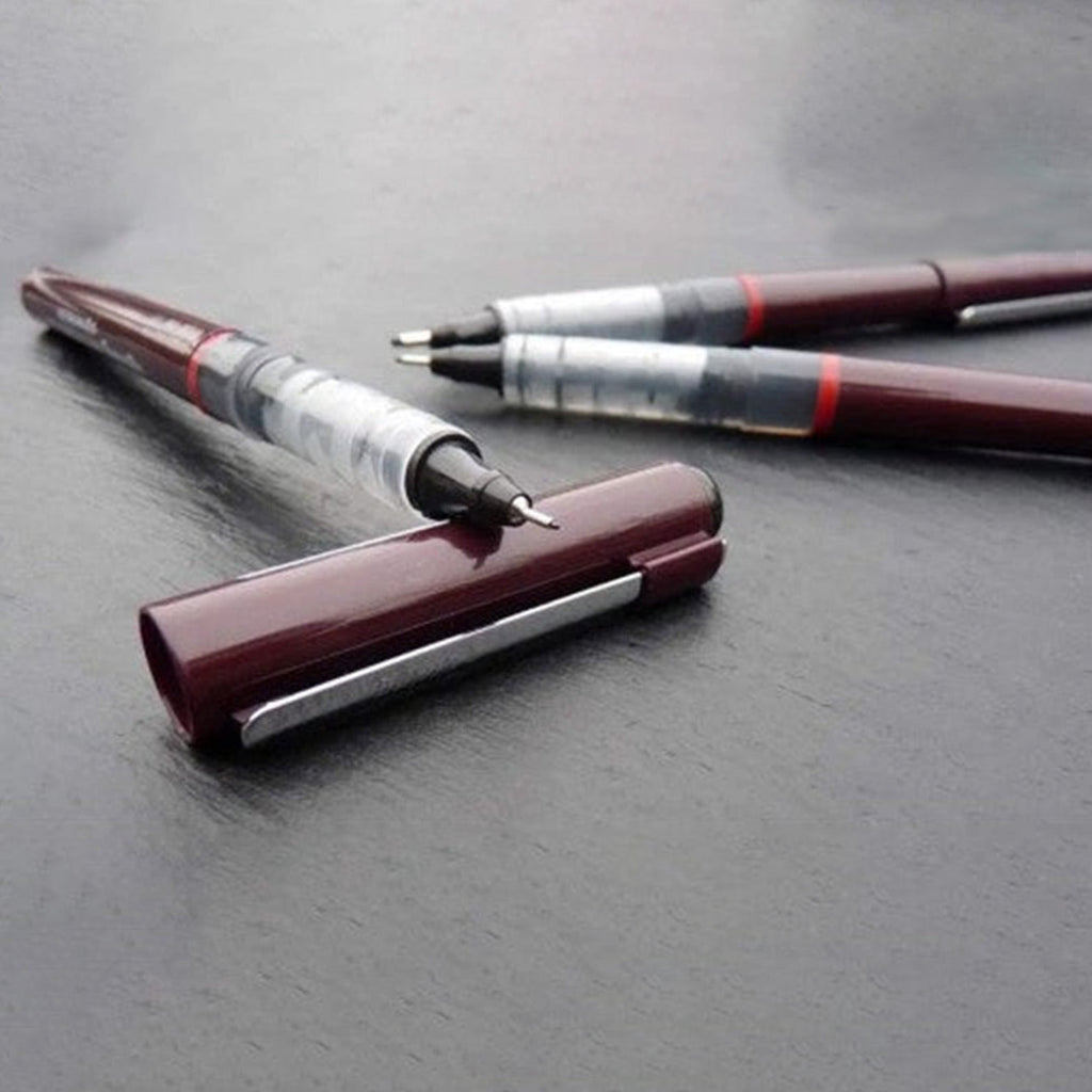 Two Rotring Tikky Graphic Fineliner with burgundy and silver accents on a gray surface
