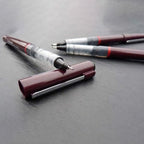 Two Rotring Tikky Graphic Fineliner with burgundy and silver accents on a gray surface